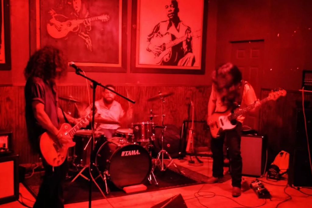 Picture of a rock band playing under red lights