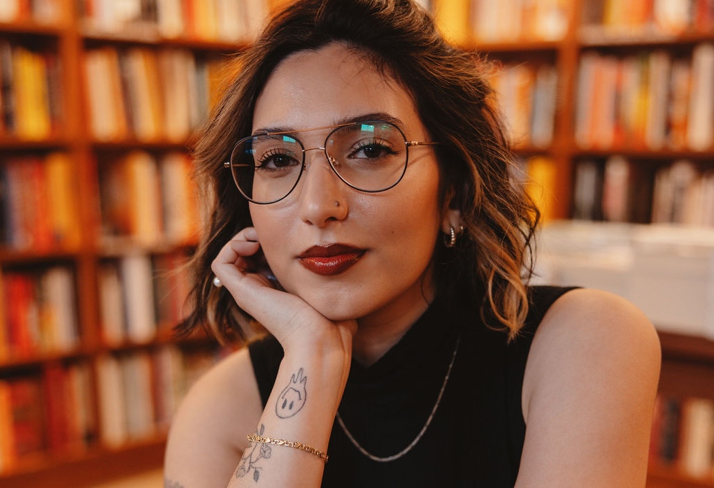 photo of a woman in glasses, a black sleeveless blouse, and dark red lipstick