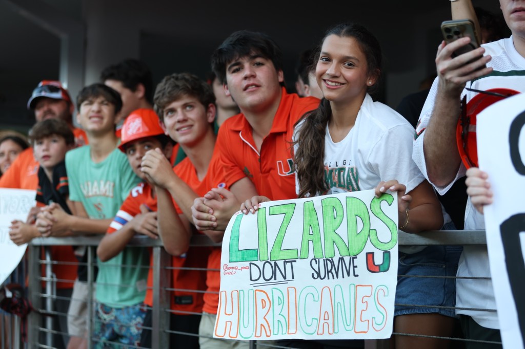 A group of young UM fans. One holds a sign reading, "Lizards don't survive hurricanes."