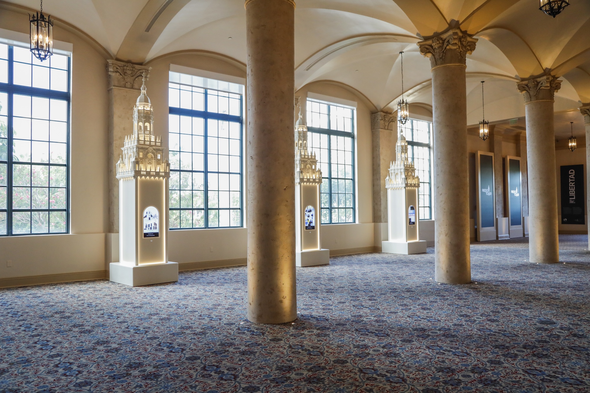 a museum hall with columns and three replicas of Miami's Freedom Tower