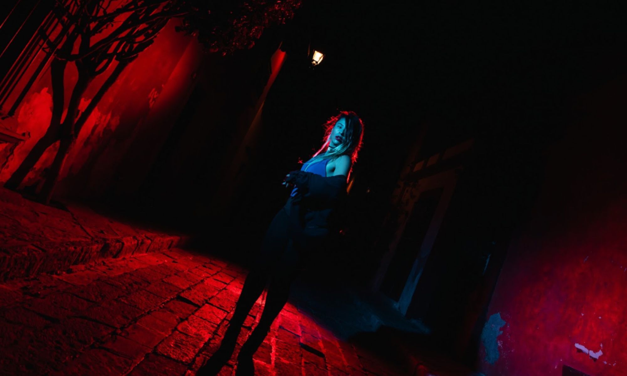 Picture of a woman in an alley under red light.