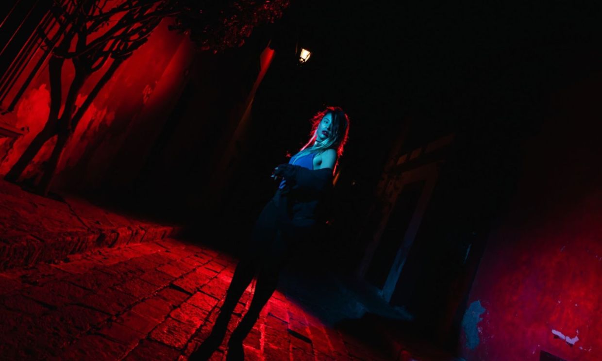 Picture of a woman in an alley under red light.