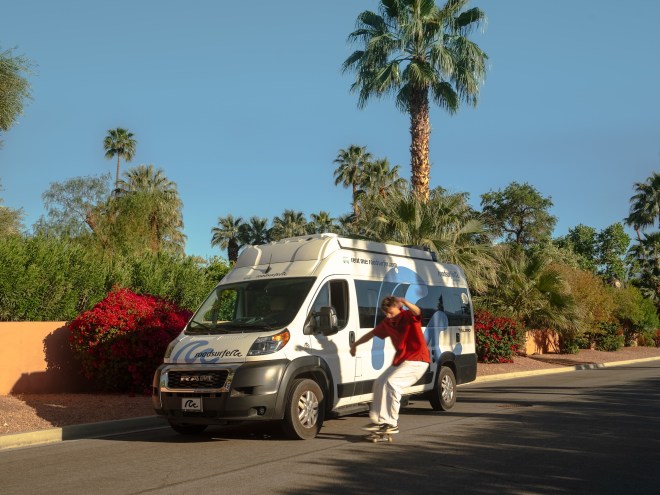 a young man skateboards next to a camper van