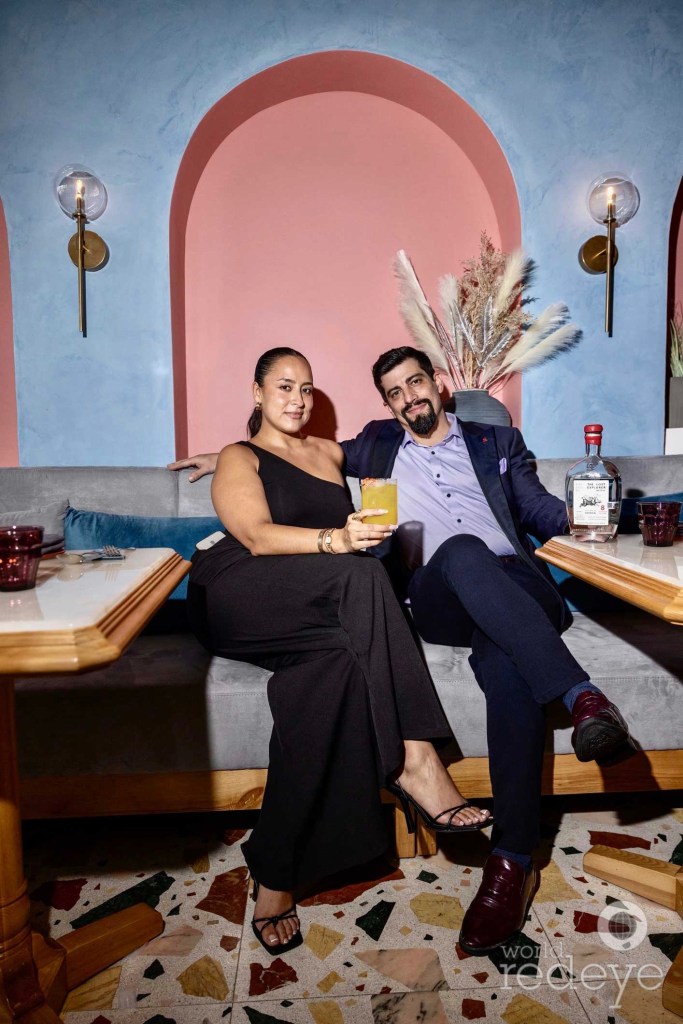 two people posing with cocktails on the couch of a restaurant lounge