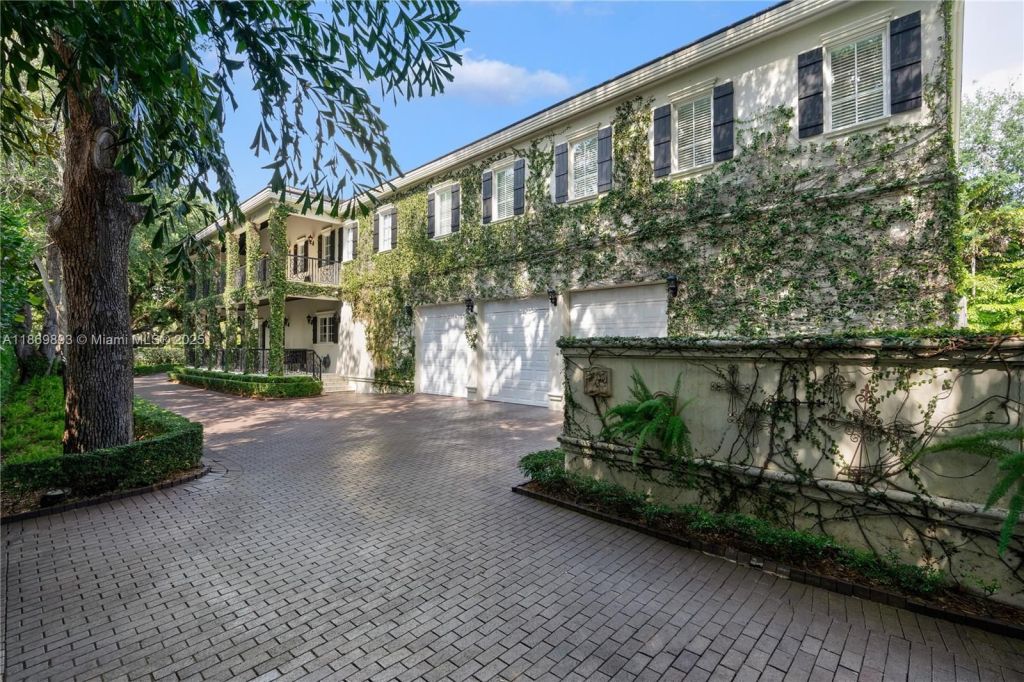Depicted is a brick driveway leading up to a three-car garage at this stately Coral Gables mansion.