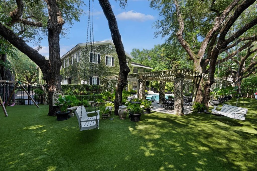 A manicured side yard is depicted with a loveseat tree swing and multiple seating areas under the cover of sprawling oaks.