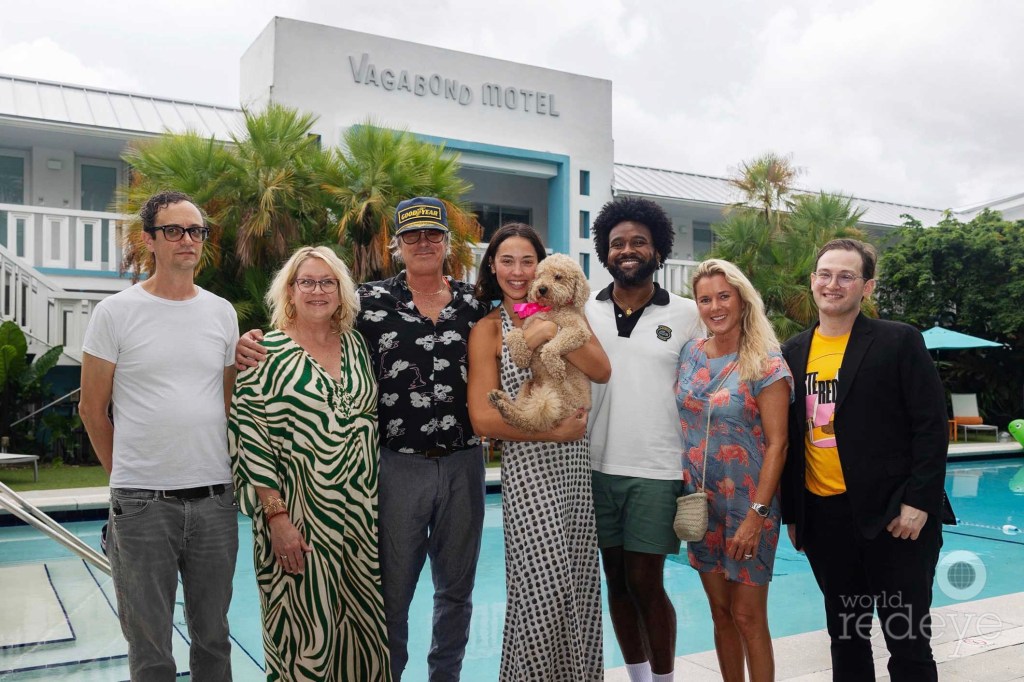 a group of people (one holding a dog) poses in front of a pool