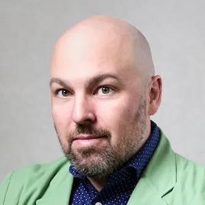 photo of a bald man wearing a with a green jacket