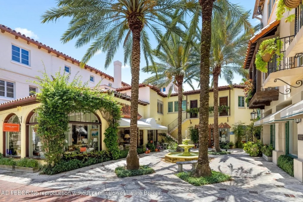 Depicted is a Mediterranean-style courtyard with four palm trees towering over plants in every nook and cranny.