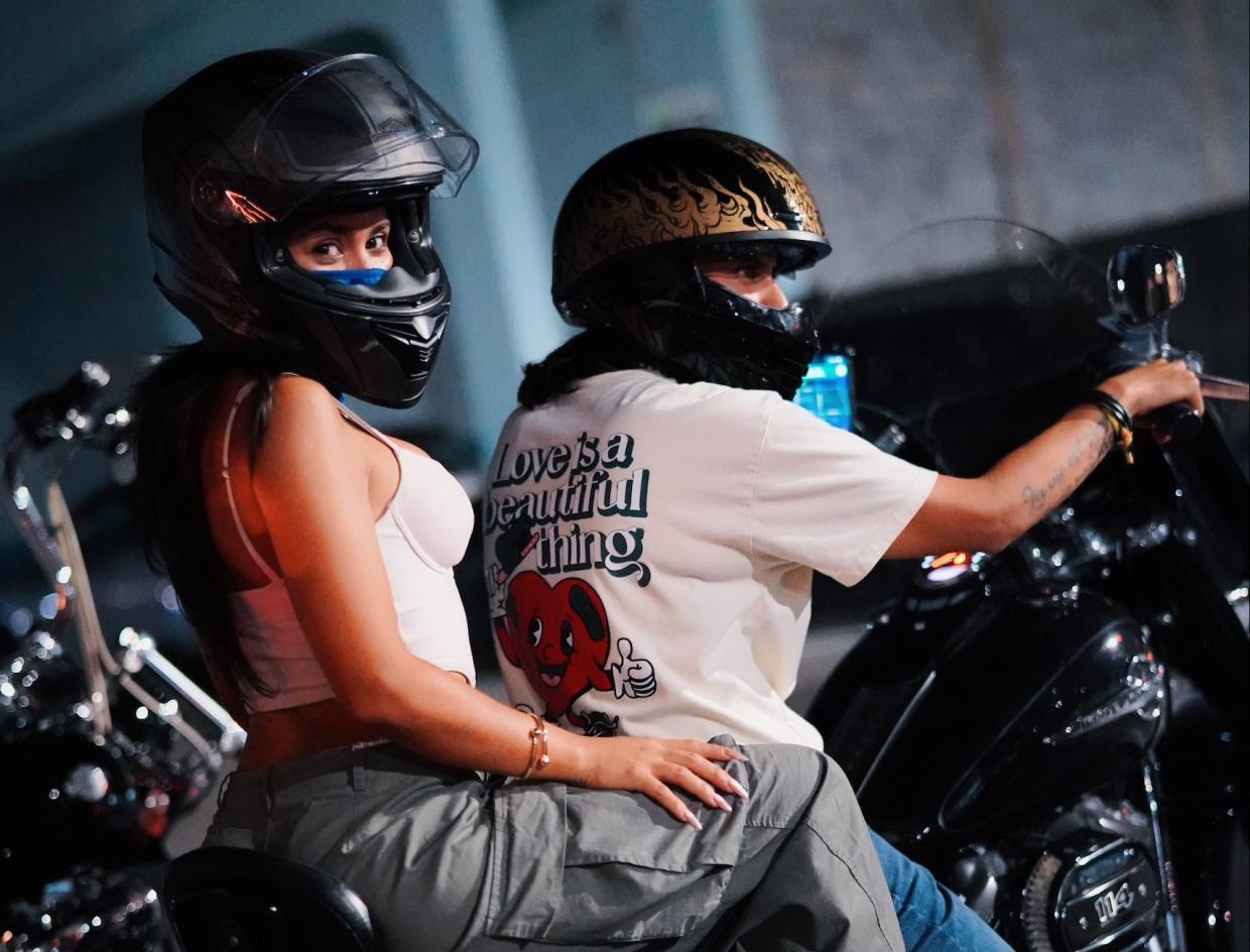 Picture of a woman and a man on a motorcycle wearing helmets.