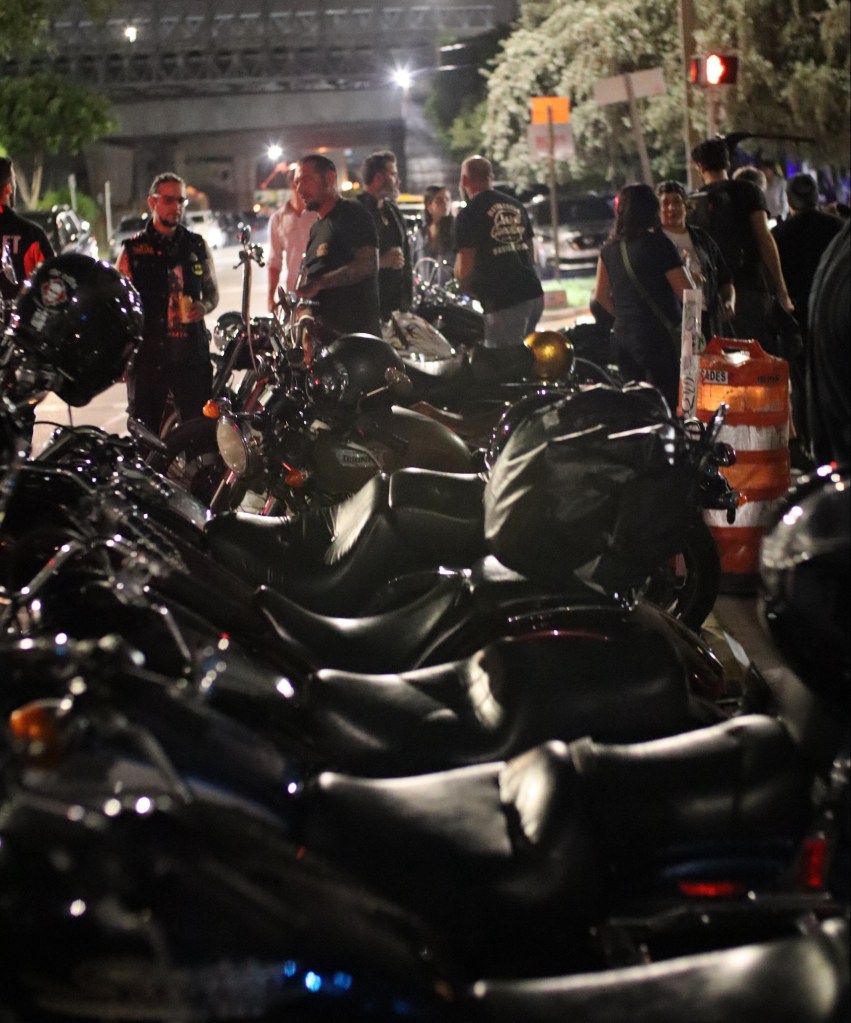 Bikers outside a bar next to their motorcycles.