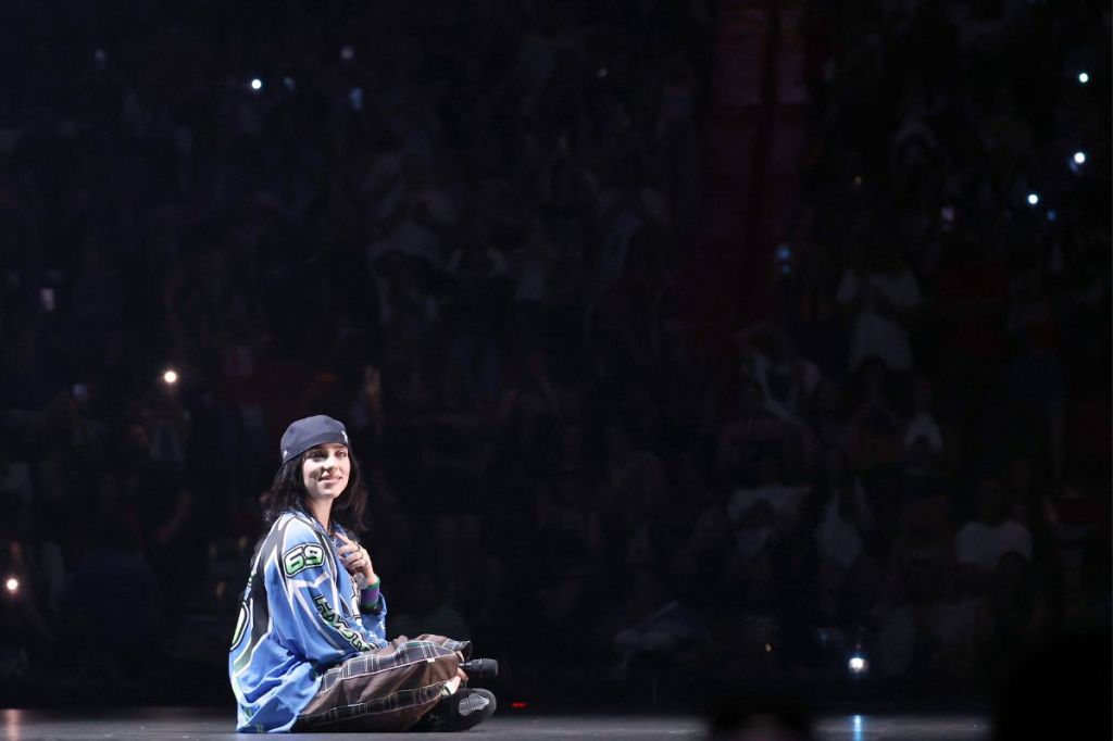 Billie Eilish sitting in the middle of a stage. 