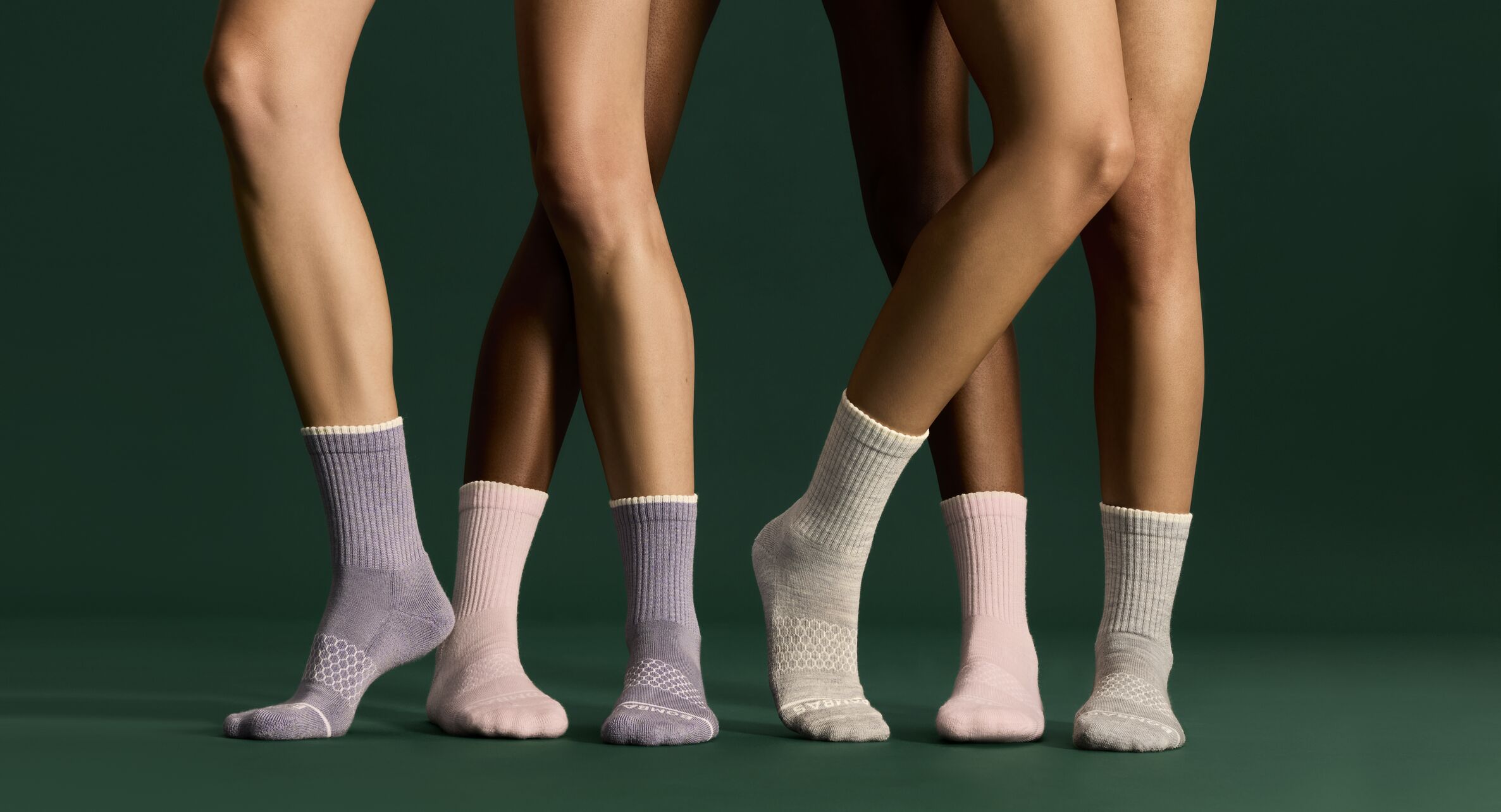 view from the knee-down of models wearing stylish socks in front of a green backdrop