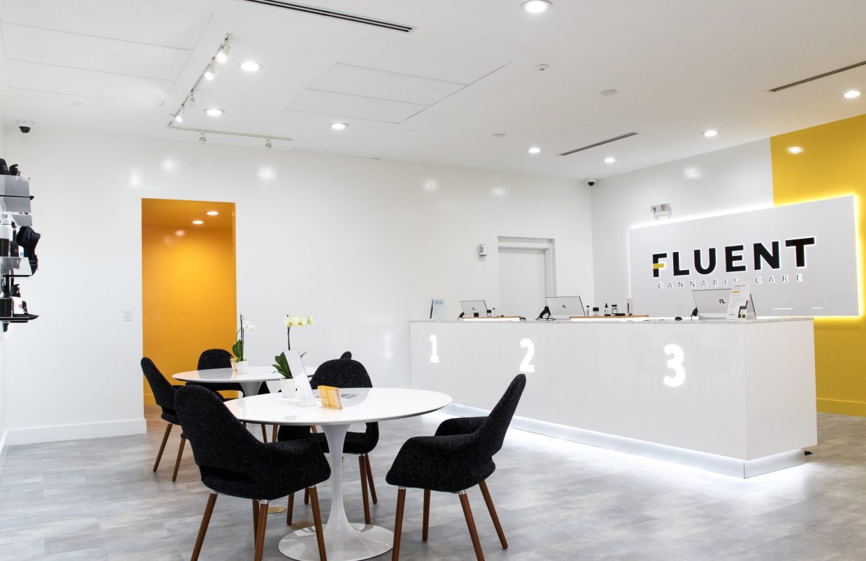 Inside Fluent Cannabis dispensary. There are two tables and black chairs. There is also a white checkout counter with 1,2, and 3.