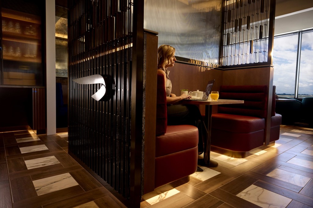 a woman sitting at a booth inside a dining room with her laptop open on the table