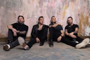 Picture of four men sitting by a wall.