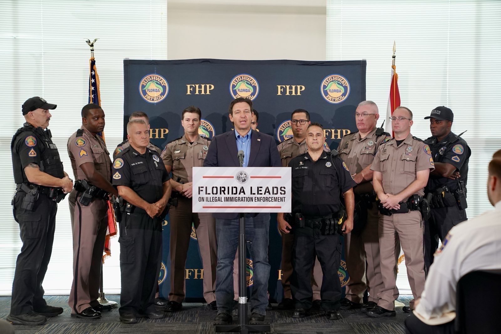 Ron DeSantis stands at a press conference surrounded by Florida Highway Patrol
