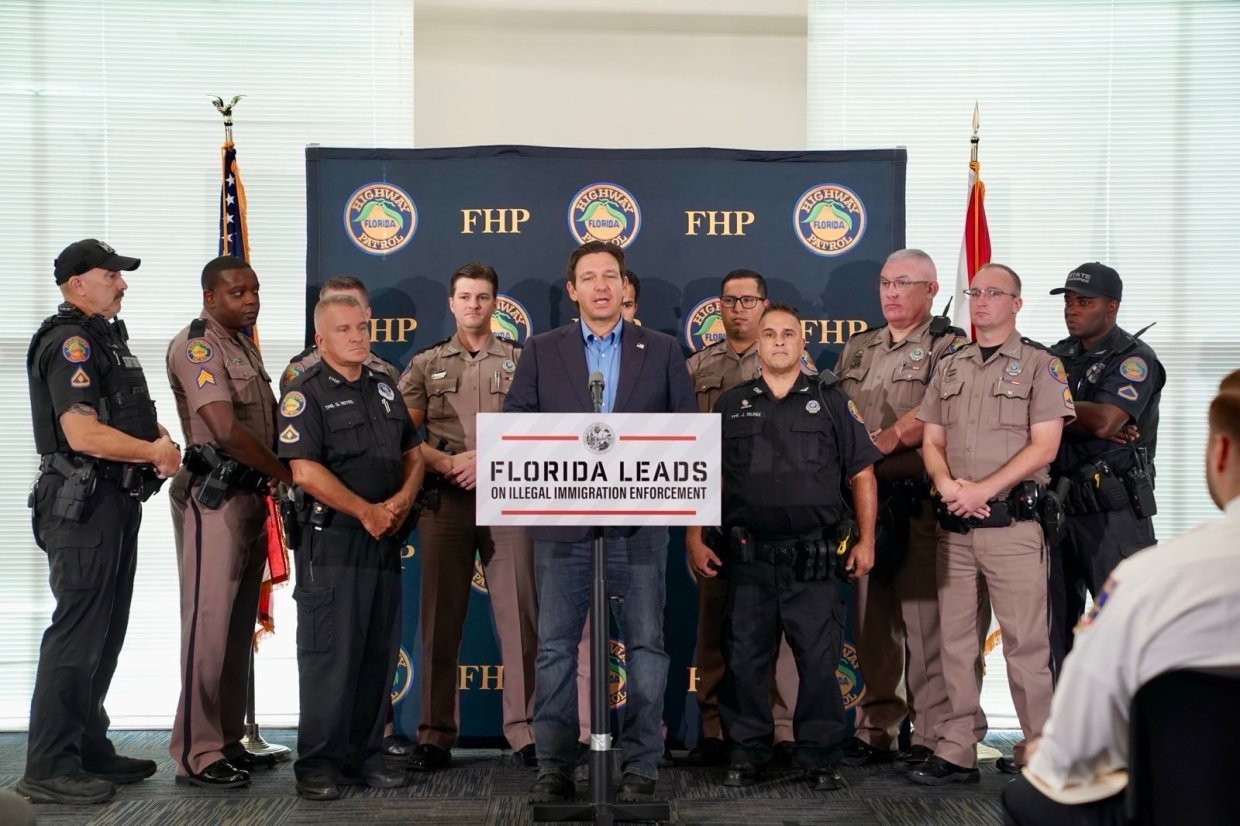 Ron DeSantis stands at a press conference surrounded by Florida Highway Patrol