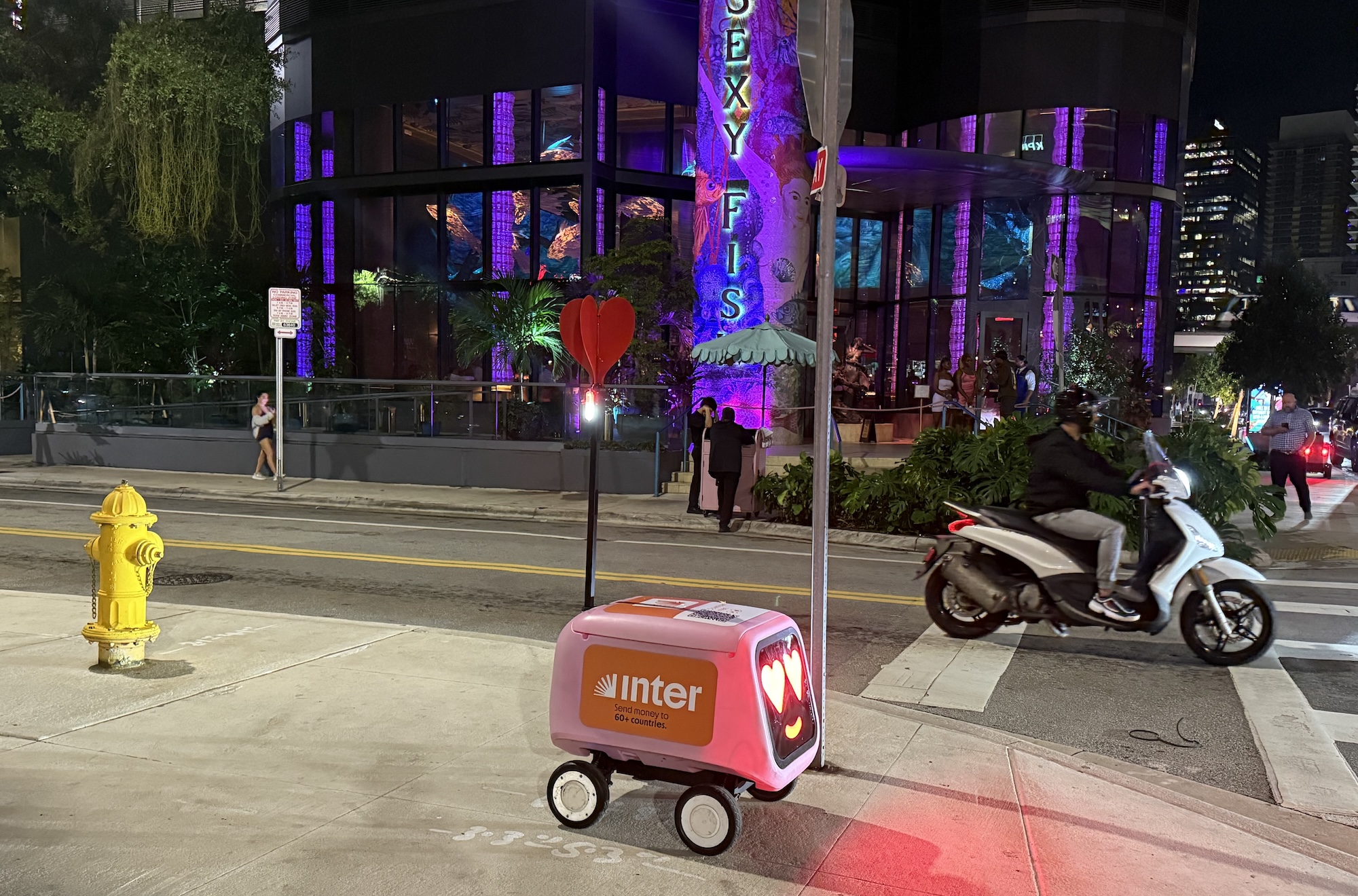 a red Inter delivery robot on a sidewalk at night