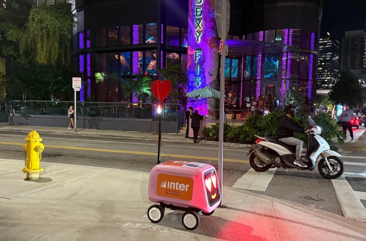 a red Inter delivery robot on a sidewalk at night