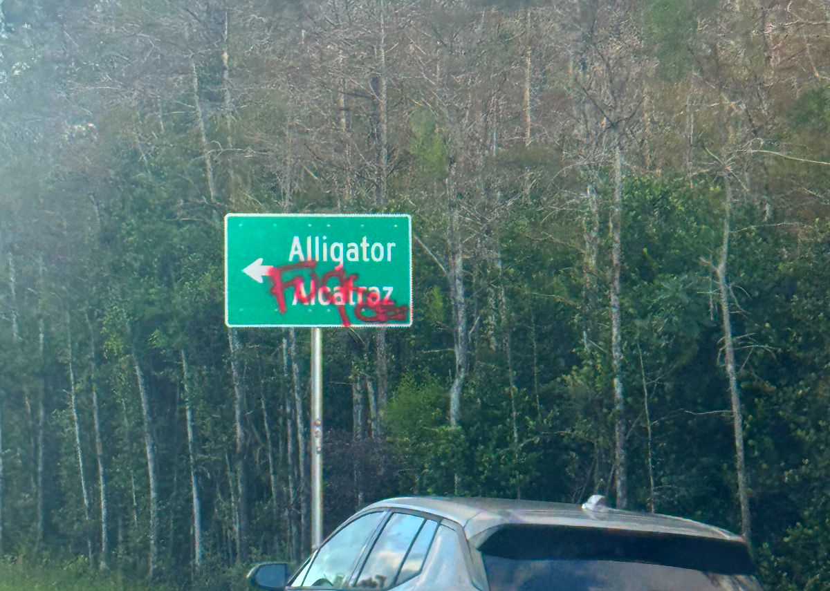 An "Alligator Alcatraz" road sign spray-painted with the words "FUCK ICE."