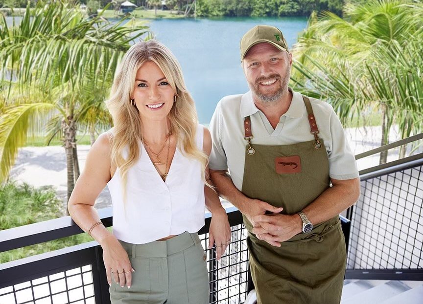 casually dressed couple on a balcony, photographed against a tropical background