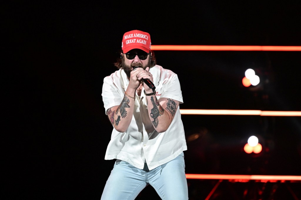 A singer on stage wearing a hat that reads Make America Great again.