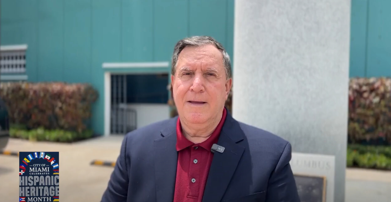 Joe Carollo looks into camera wearing navy sport jacket and red polo