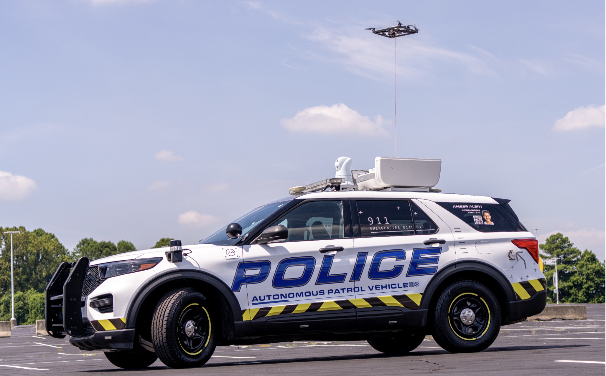Depicted is an autonomous police patrol SUV with a drone flying overhead