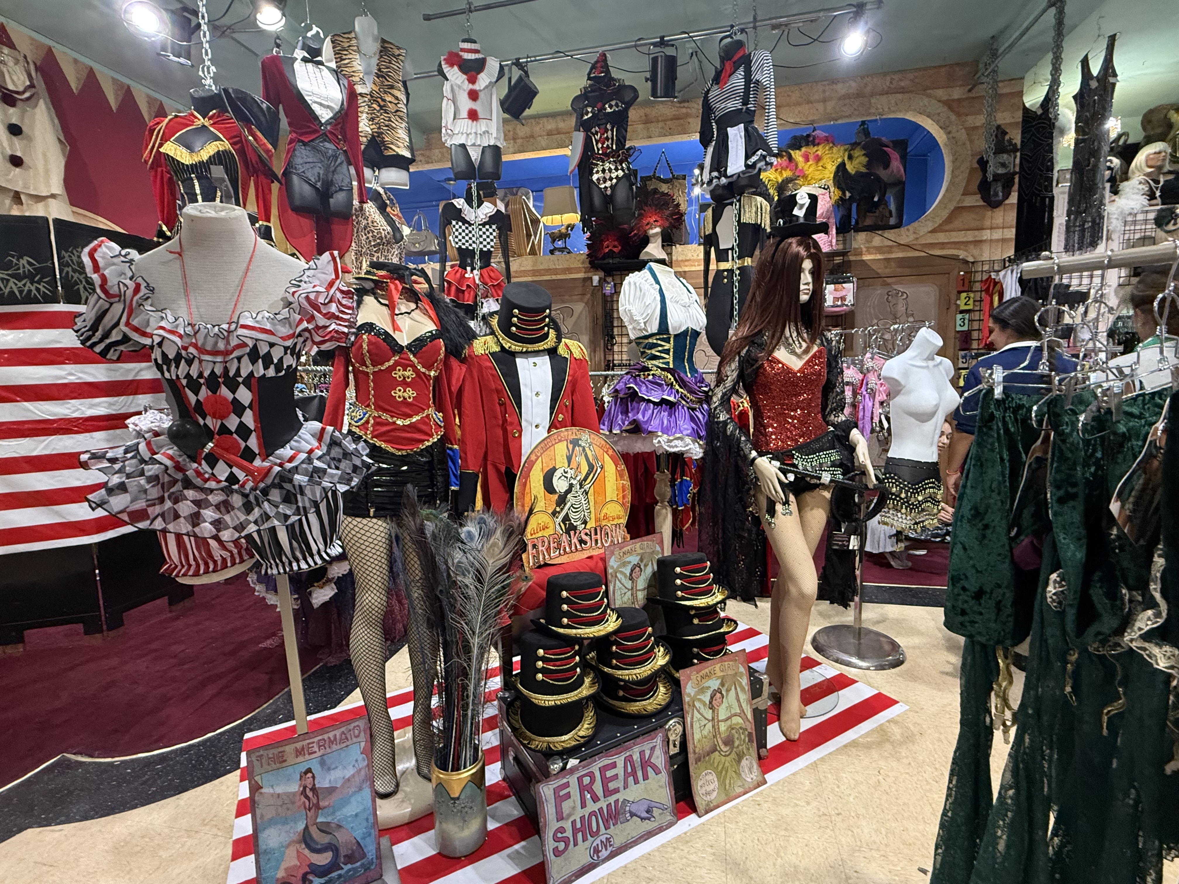 interior of a costume shop showing mannequins wearing harlequin, ringmaster, and showgirl costumes