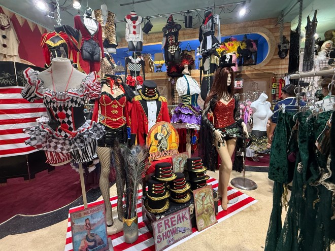 interior of a costume shop showing mannequins wearing harlequin, ringmaster, and showgirl costumes