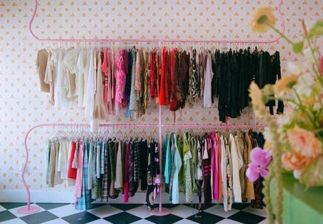 two racks of clothes on the wall of a boutique shop