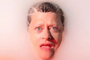 Picture of the face of a woman getting out of pink water