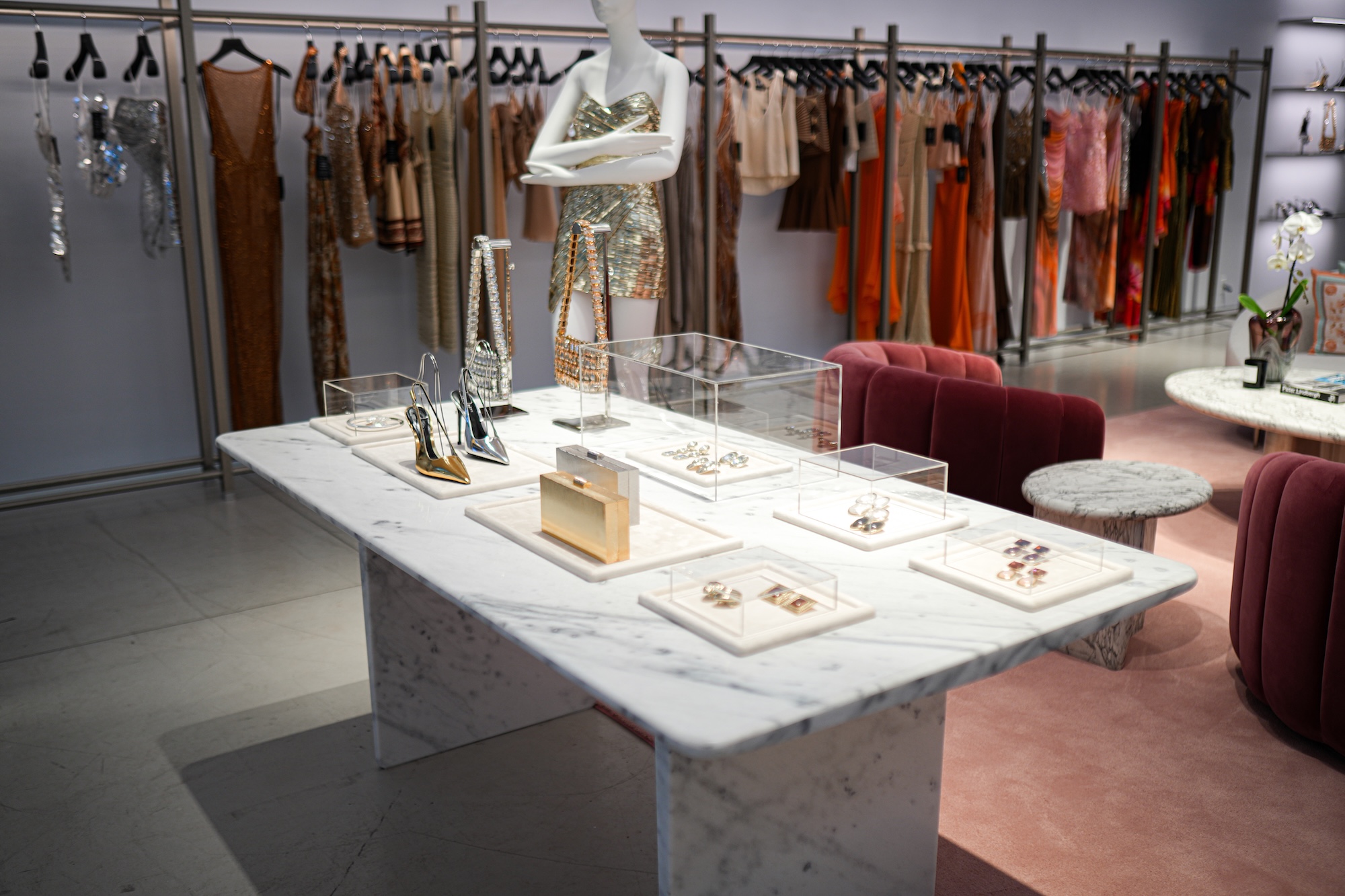 photo of the interior of a boutique shop with dresses on hangers in the background and a table with accessories in the foreground