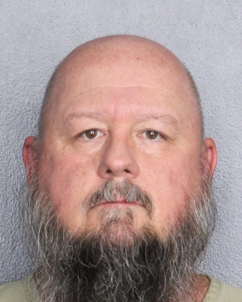 Depicted is the mugshot of a bald, white man with a long dark-and-light-gray beard