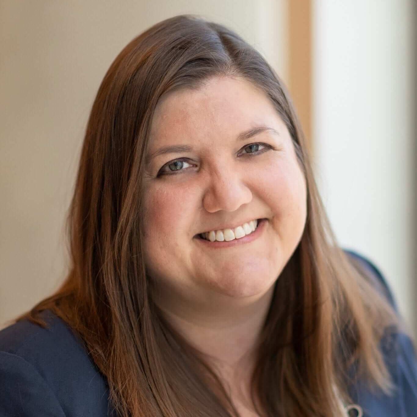 headshot of a smiling professional woman with straight brown hair