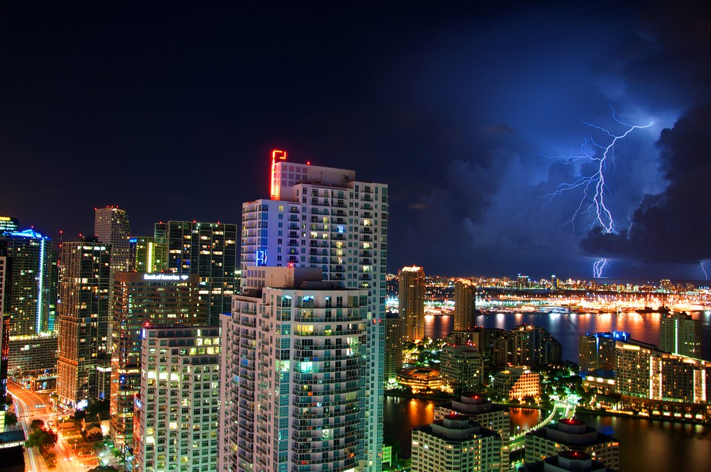 lightning strikes in the clouds hovering above the Miami skyline at night