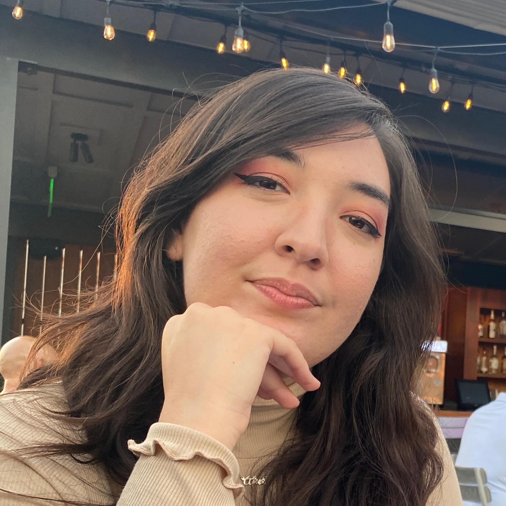 headshot of a woman with dark hair sitting at an outdoor dining establishement