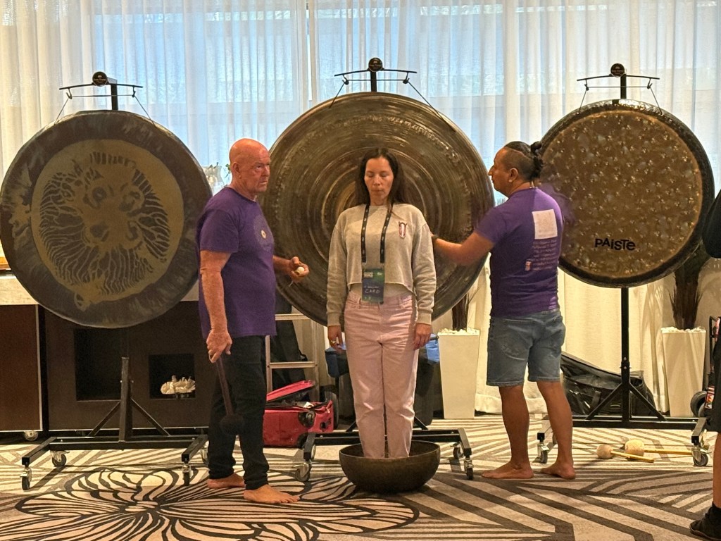 photo of a three people standing in front of three huge gongs