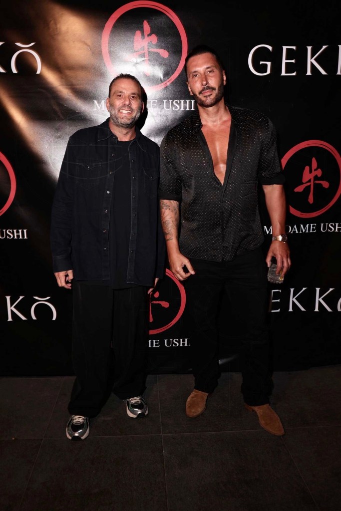 photo of two men in black outfits standing in front of a step-and-repeat with logos of restaurants Gekko and Madame Ushi