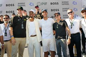 photo of six men posing in the foreground in front of an LED screen