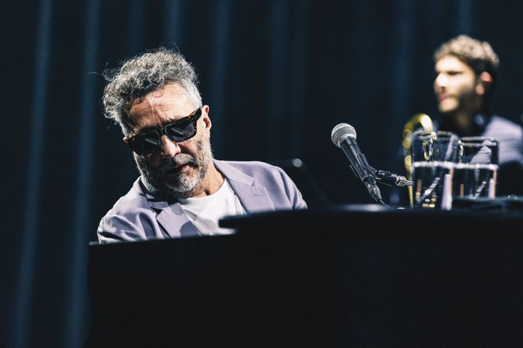 A man with sunglasses playing piano. 