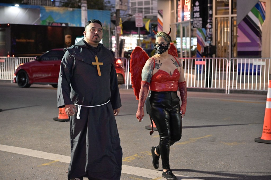 photo of a man dressed like a priest and a woman drssed like the devil on Halloween