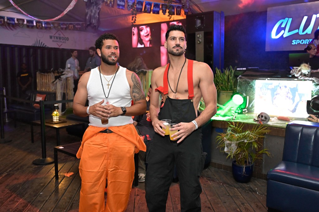 photo of a man in a white t-shirt and another in overalls at a party