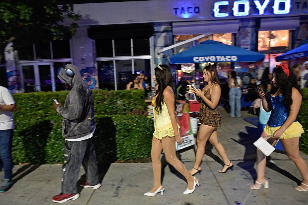 photo of people in Halloween costumes walk on the street in front of Coyo Taco in Miami's Wynwood neighborhood