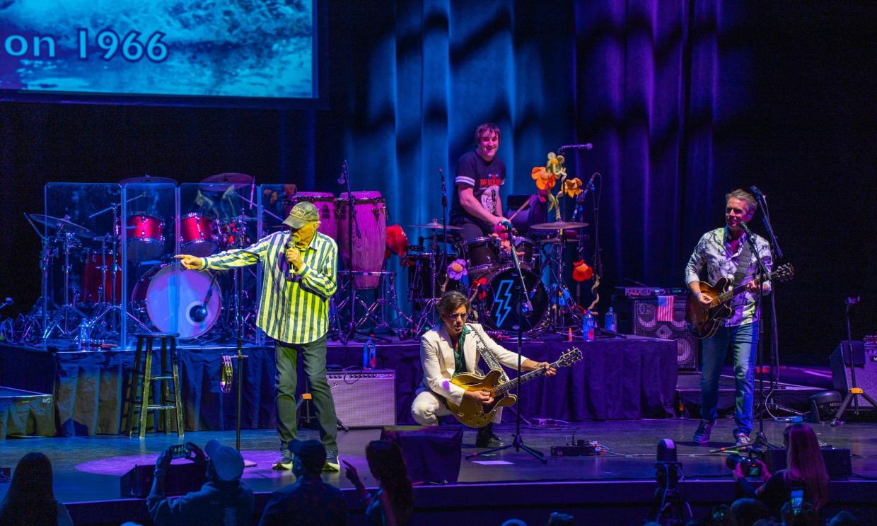 Photo of a four piece band performing on stage.