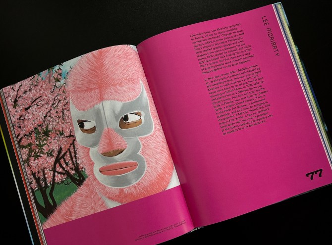 photo of an opened book showing a painting of a lucha libre wrestler with a pink and silver mask next to pink cherry blossoms