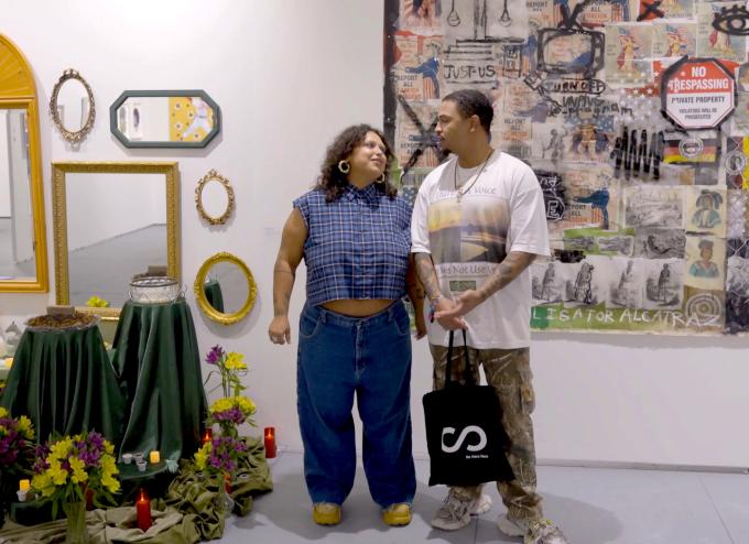 photo of two artists looking at each other between their two installations inside a gallery