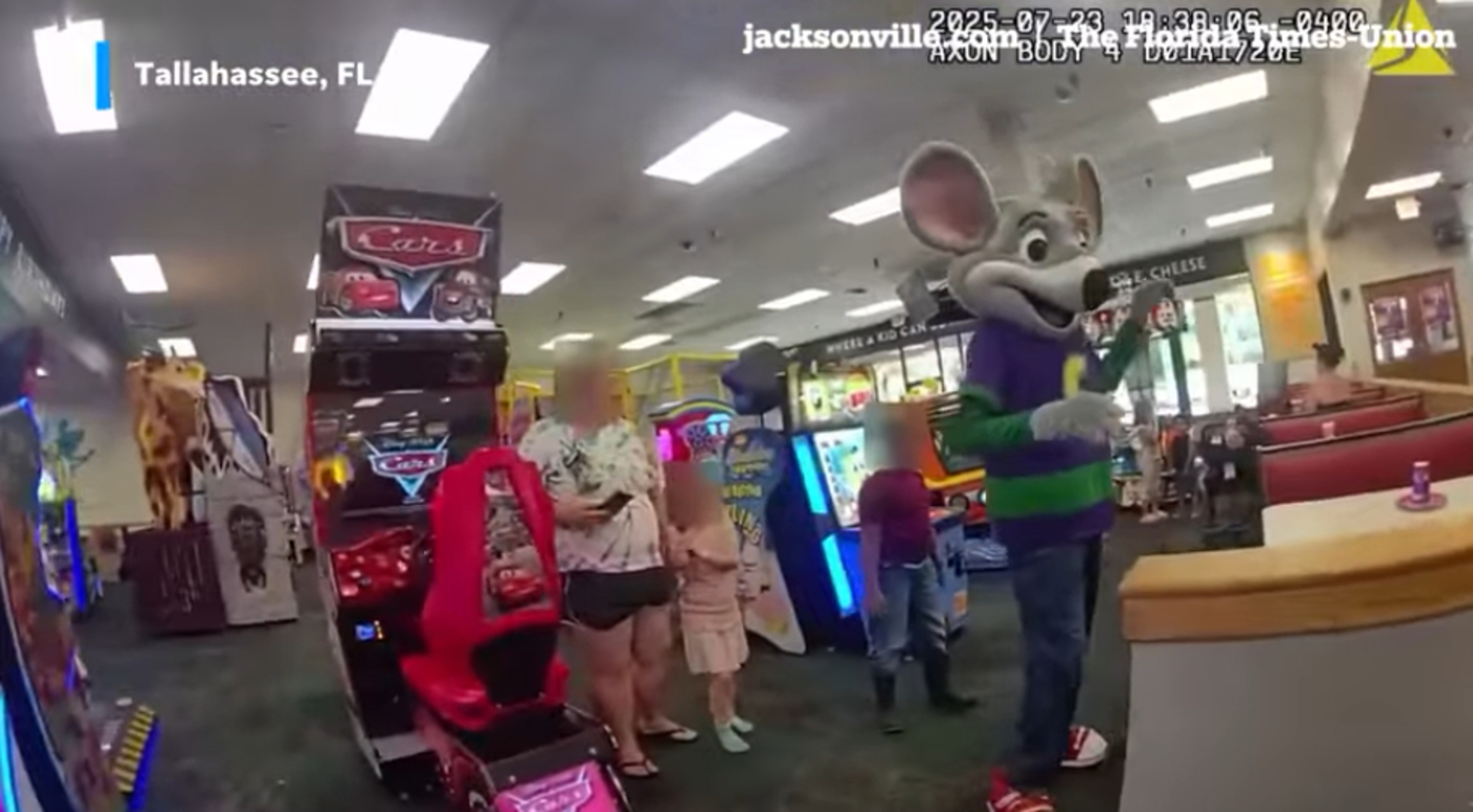 Body-camera footage of Chuck E. Cheese mascot surrounded by children with blurred faces inside the arcade