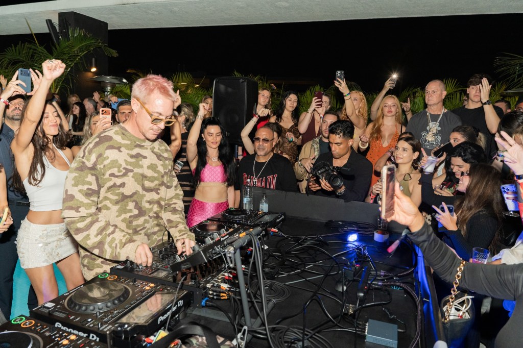 Photo of a DJ surrounded by people.